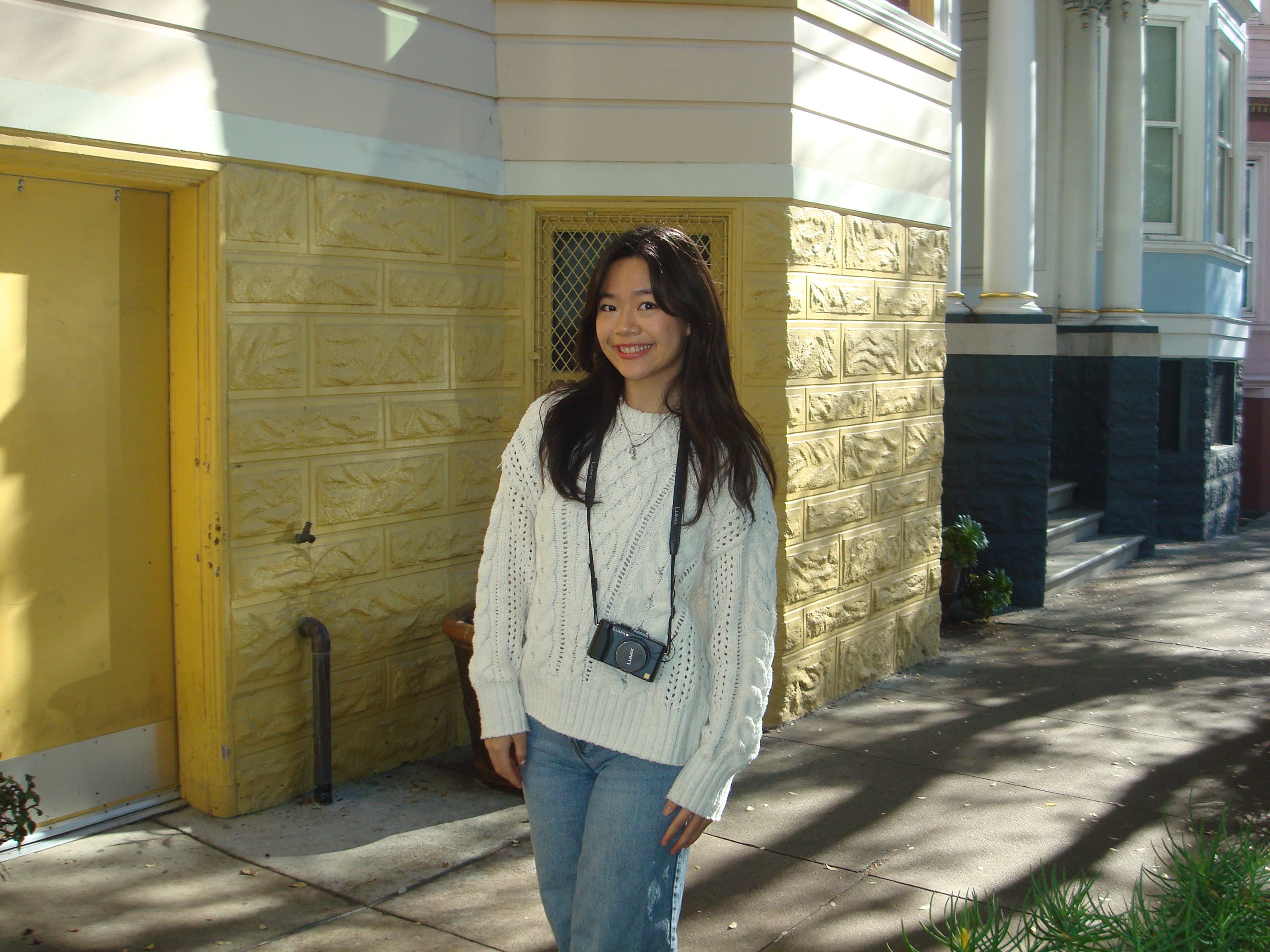 Doris Cao standing on a sidewalk in front of a yellow building